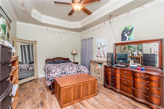 bedroom with ceiling fan, crown molding, a raised ceiling, light hardwood / wood-style floors, and a textured ceiling