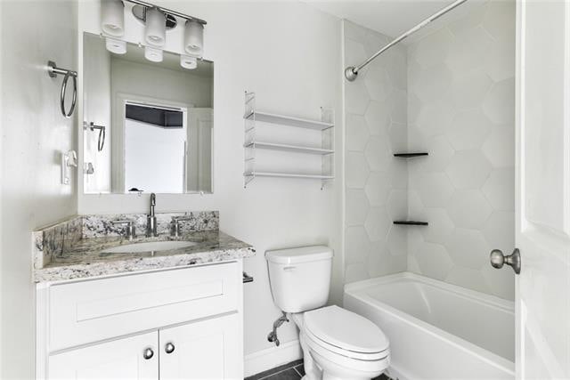 full bathroom featuring tiled shower / bath combo, toilet, and large vanity