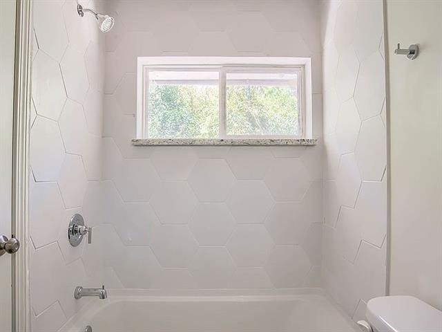 bathroom with toilet and tiled shower / bath combo