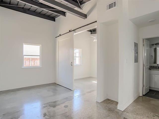 unfurnished room featuring a barn door and a towering ceiling