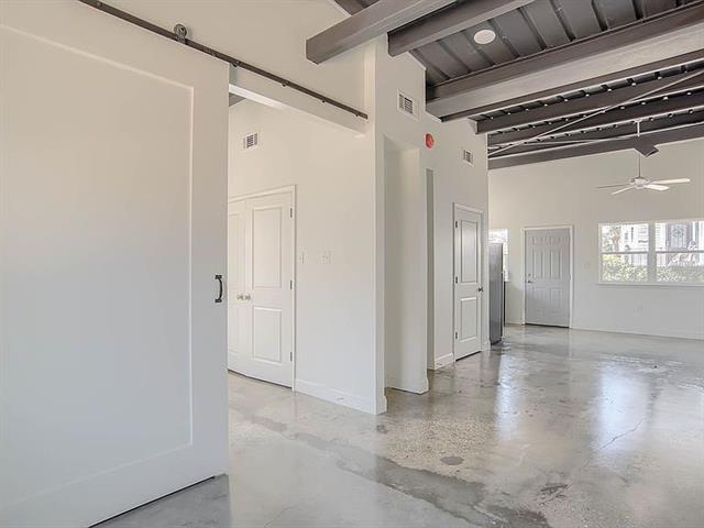 unfurnished room with a barn door, ceiling fan, and high vaulted ceiling