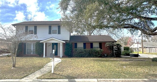 traditional-style home featuring brick siding and a front yard