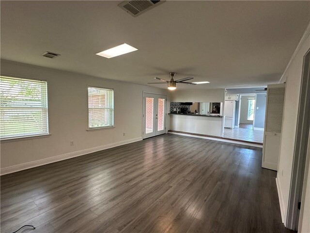 unfurnished living room with plenty of natural light, ceiling fan, and dark hardwood / wood-style flooring