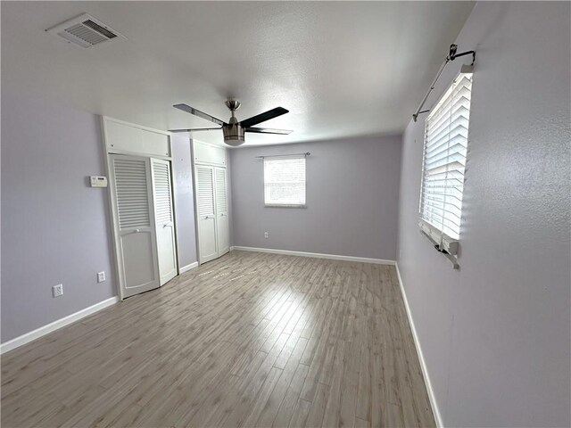 unfurnished bedroom featuring two closets, ceiling fan, and hardwood / wood-style floors