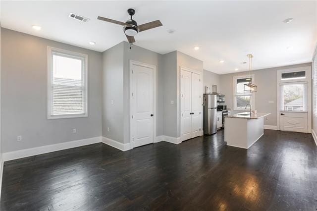 kitchen with decorative light fixtures, dark hardwood / wood-style flooring, stainless steel fridge, and a wealth of natural light