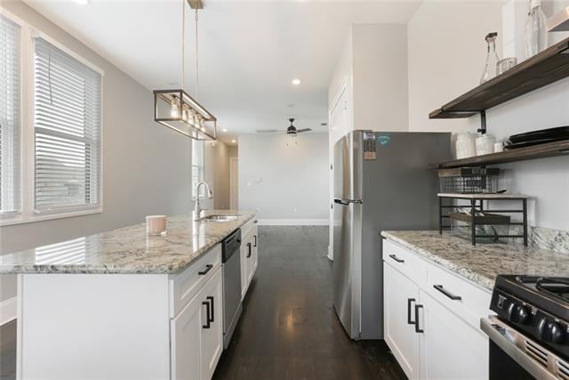 kitchen with dark hardwood / wood-style floors, ceiling fan, white cabinetry, and a center island with sink