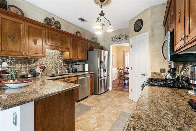 kitchen with light hardwood / wood-style flooring, a textured ceiling, backsplash, appliances with stainless steel finishes, and decorative light fixtures