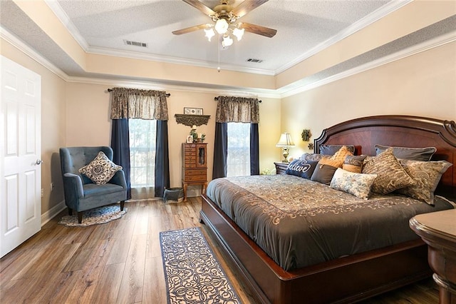 bedroom featuring a textured ceiling, wood-type flooring, crown molding, and ceiling fan