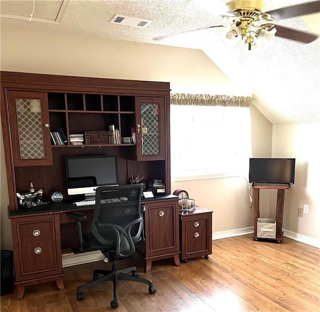 office area featuring light wood-type flooring, ceiling fan, vaulted ceiling, and a textured ceiling