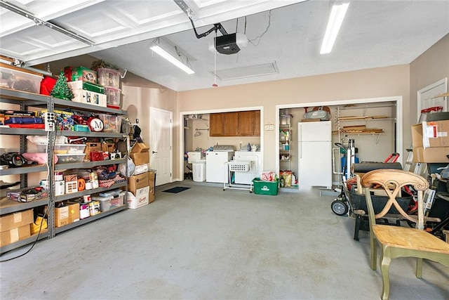 garage with washing machine and clothes dryer, white fridge, and a garage door opener