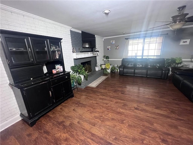 living room with a fireplace, brick wall, ceiling fan, ornamental molding, and dark hardwood / wood-style flooring