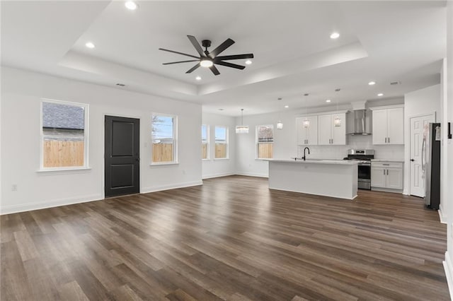 unfurnished living room with ceiling fan, dark hardwood / wood-style floors, a raised ceiling, and sink