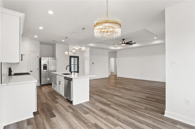 kitchen featuring an island with sink, hanging light fixtures, appliances with stainless steel finishes, and dark hardwood / wood-style floors