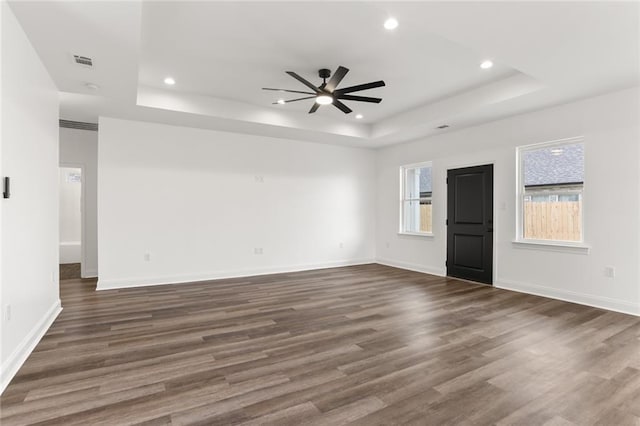 spare room with ceiling fan, dark wood-type flooring, and a tray ceiling