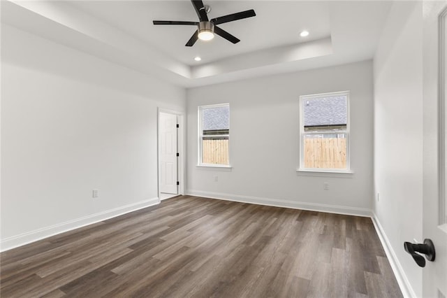 unfurnished room featuring dark hardwood / wood-style floors, ceiling fan, and a tray ceiling