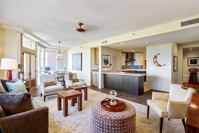 living room with ceiling fan with notable chandelier and dark hardwood / wood-style floors