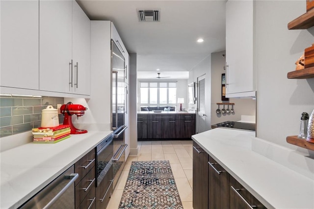 kitchen featuring white cabinets, decorative backsplash, light tile patterned floors, and dark brown cabinets