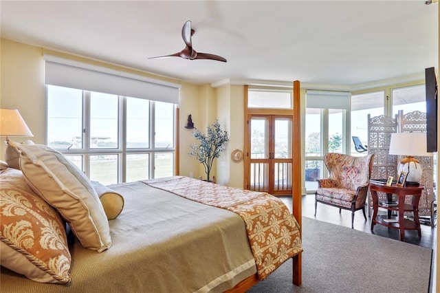 bedroom with a wall of windows and ceiling fan