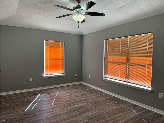 empty room with dark hardwood / wood-style flooring, ceiling fan, a textured ceiling, and lofted ceiling