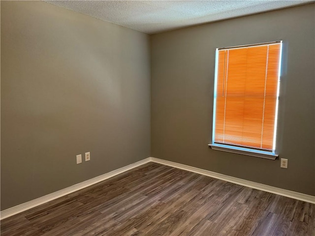 spare room featuring dark hardwood / wood-style flooring and a textured ceiling