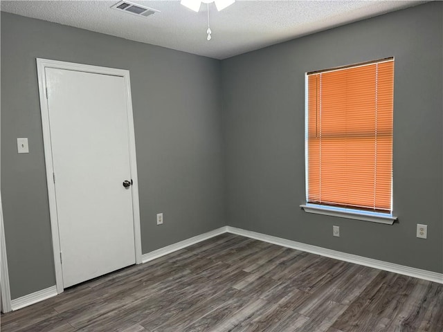 spare room featuring a textured ceiling, ceiling fan, and dark wood-type flooring