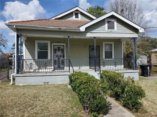 bungalow featuring covered porch and a front lawn