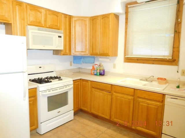 kitchen featuring white appliances, sink, and light tile floors