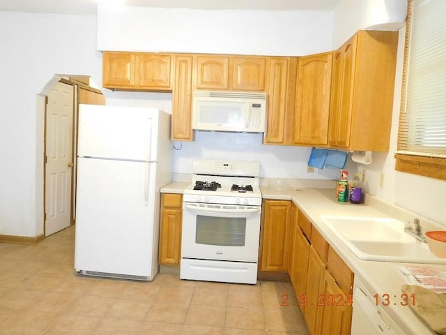 kitchen featuring white appliances, sink, and light tile floors