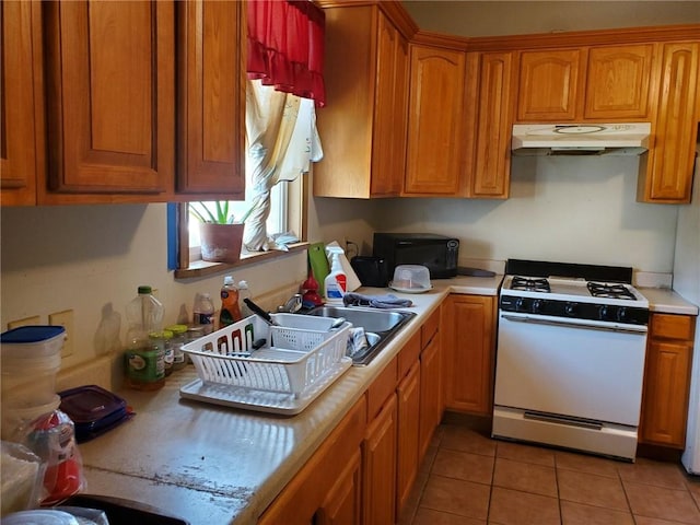 kitchen featuring sink, light tile floors, and white gas stove