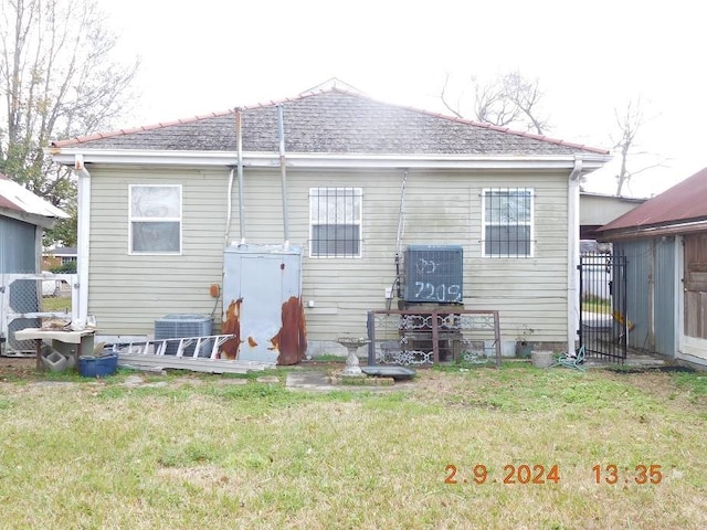 rear view of house featuring a lawn and central air condition unit