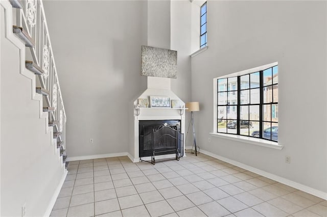 unfurnished living room with light tile patterned flooring and a towering ceiling