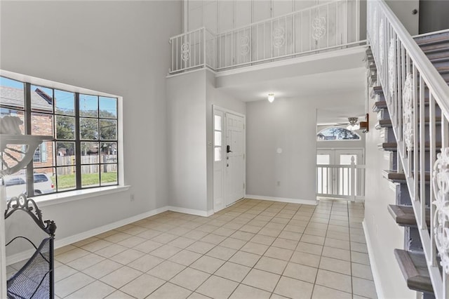 entryway featuring a towering ceiling, light tile patterned floors, and ceiling fan