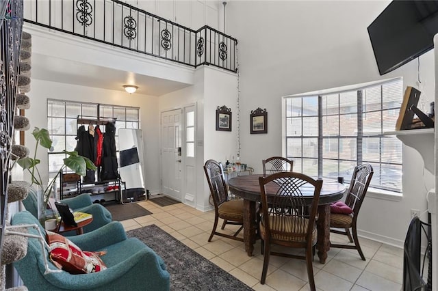 dining area with a towering ceiling, light tile patterned floors, and a wealth of natural light