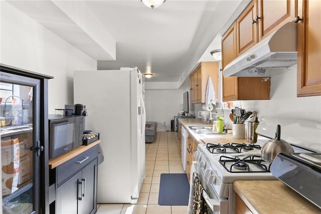 kitchen with white refrigerator, light tile patterned flooring, and range