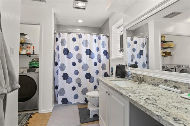 bathroom featuring tile patterned floors, toilet, vanity, and washer / clothes dryer