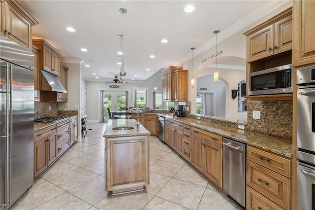 kitchen featuring sink, appliances with stainless steel finishes, kitchen peninsula, an island with sink, and pendant lighting