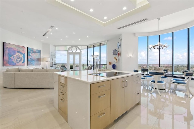 kitchen with light tile flooring, floor to ceiling windows, a chandelier, and a kitchen island with sink