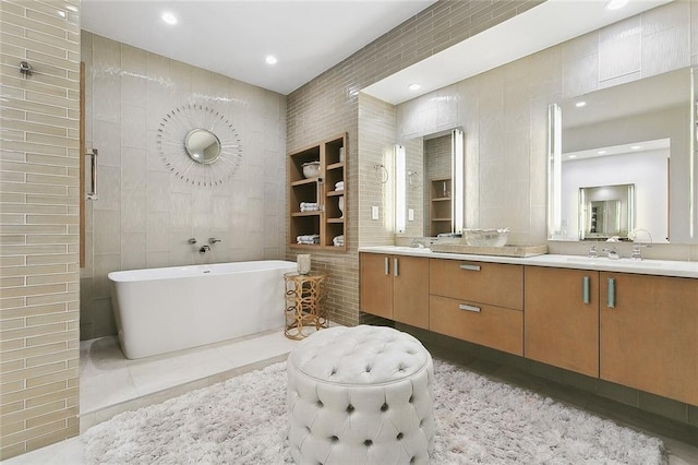 bathroom with double sink vanity, tile flooring, a bathtub, tile walls, and built in shelves