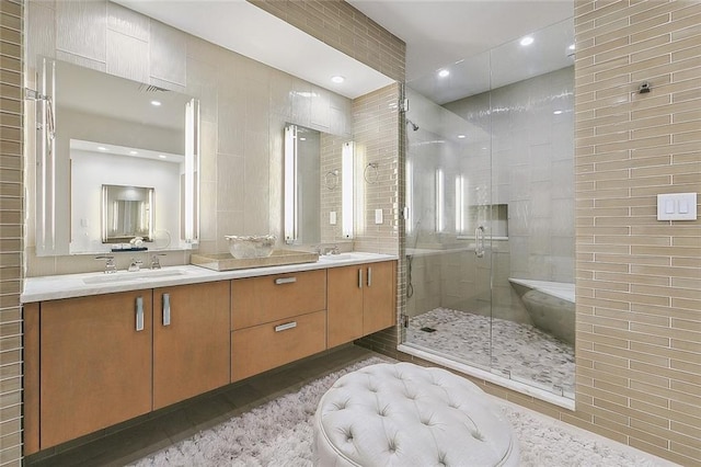 bathroom with tile flooring, dual sinks, a shower with door, and large vanity