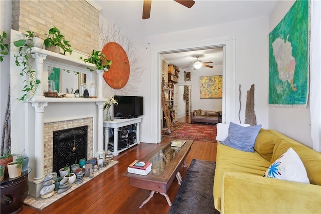 living room with brick wall, dark hardwood / wood-style floors, and ceiling fan