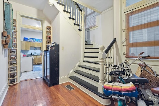 stairs with sink, washer / clothes dryer, and dark wood-type flooring