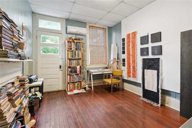 miscellaneous room featuring dark hardwood / wood-style flooring, a paneled ceiling, and a wall unit AC