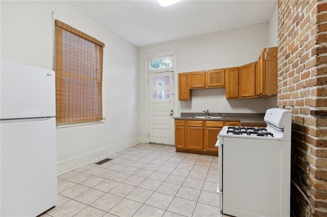 kitchen with light tile flooring, white appliances, and sink