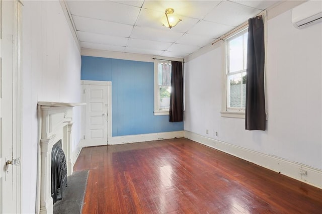 unfurnished living room featuring a wall mounted AC, dark hardwood / wood-style floors, and a drop ceiling