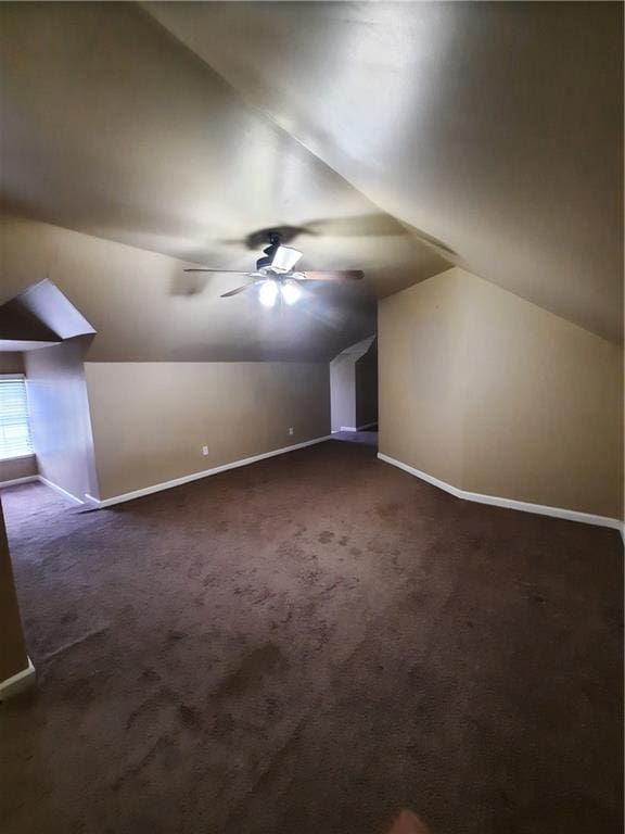 additional living space with ceiling fan, lofted ceiling, and dark colored carpet