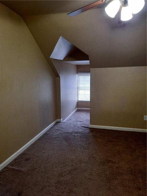 additional living space with vaulted ceiling, dark colored carpet, and ceiling fan