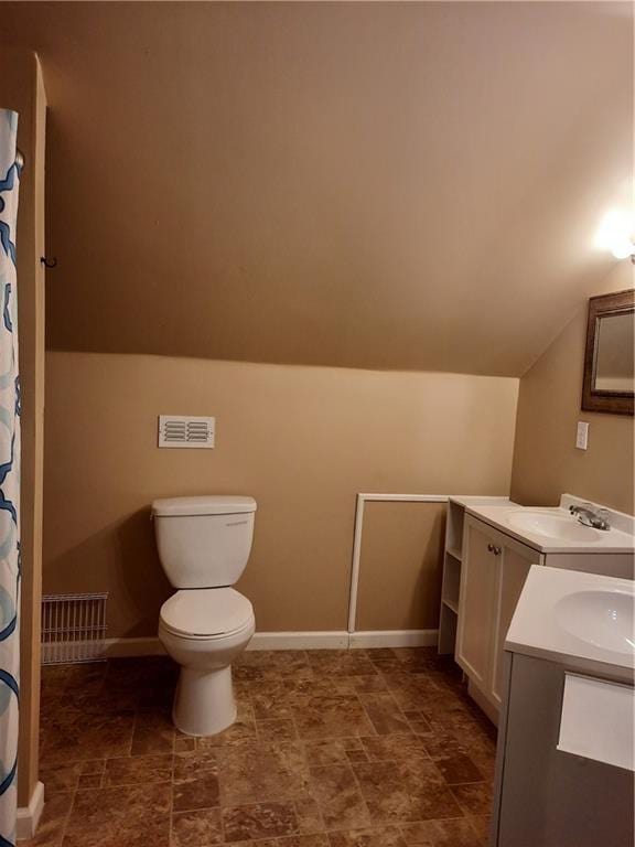 bathroom with lofted ceiling, vanity, and toilet