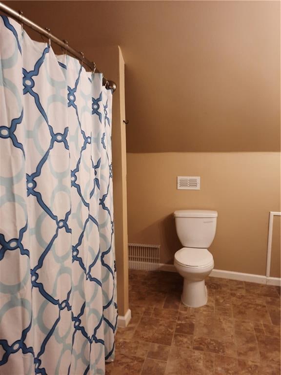 bathroom featuring curtained shower and toilet