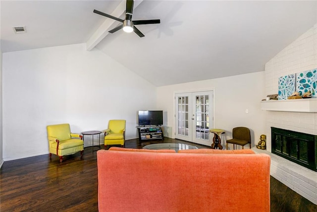 living room with dark wood-type flooring, ceiling fan, a fireplace, brick wall, and lofted ceiling with beams