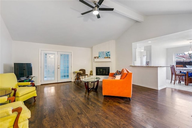 living room featuring a brick fireplace, ceiling fan with notable chandelier, brick wall, lofted ceiling with beams, and dark hardwood / wood-style floors